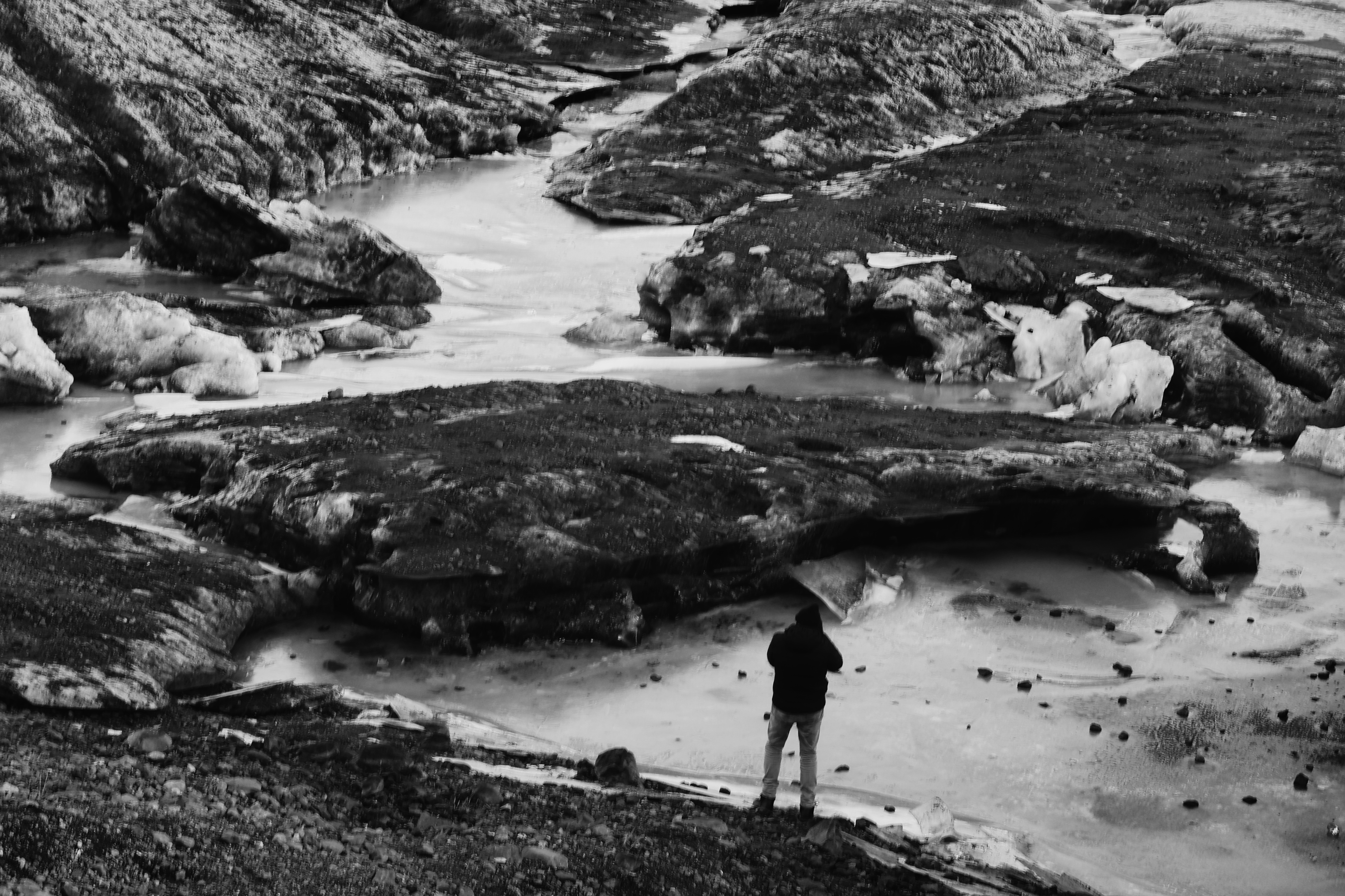 Eenzame figuur aan een gletsjerrivier in IJsland, zwart-wit